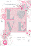 This anniversary card presents a gentle celebration of enduring romance, its design as soft and intimate as an evening stroll through Fulham's quieter side streets. At the card's centre, the word LOVE is spelled out in raised, softly shimmering glitter, the surface blending pale blush pink with hints of silver. The letter forms are rounded and inviting, with the O subtly echoed by a central heart-shaped emphasis, creating a focal point that draws the eye and invites touch. Around this central word, a spray of delicate blossoms unfurls in blush, mauve, and soft ivory tones, their edges feathered and almost watercolour in appearance. The flowers are linked by flowing vines and fine tendrils, suggesting the effortless grace of an English spring garden, much like the borders hidden behind period houses off North End Road or near Parsons Green. Tiny flourishes-scattered petals, gentle curls, and discreet butterflies-add a sense of motion, as if the design is drifting lightly across the card. The palette is a dreamy blend of pastel pinks and silvery greys, giving the whole piece a quiet, treasured feel. In a refined, graceful script, the words On Our Anniversary and I love you today and always appear, the lettering slender and carefully spaced so it feels handwritten and personal. The overall impression is of a keepsake chosen with care, the floral motif standing in for a romantic bouquet placed on a dining table in Fulham, marking another year of shared life with something soft, sincere, and beautifully understated.
